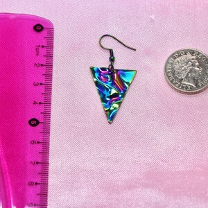 May include: A pair of iridescent triangle earrings with a silver hook. The earrings are approximately 2 cm in length.