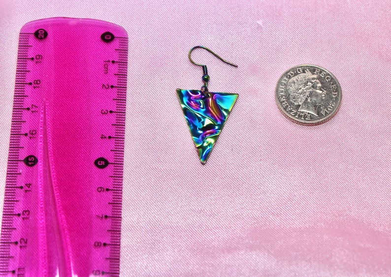 May include: A pair of iridescent triangle earrings with a silver hook. The earrings are approximately 2 cm in length.