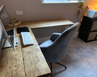 Könnte beinhalten: Ein Ecktisch mit einer rustikalen Holzplatte und Haarnadelbeinen. Ein grauer Samtstuhl steht am Tisch, und ein Computermonitor, eine Tastatur und eine Maus befinden sich auf dem Tisch.