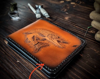 May include: A brown leather wallet with a black stitched border. The wallet has a detailed image of a fish on the front. The text "Add your name or initials" is written on the bottom of the image.