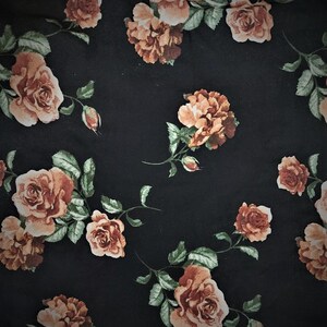 May include: Black fabric with a repeating pattern of orange roses and green leaves.