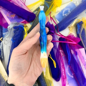 Könnte beinhalten: Ein mehrfarbiger Stift aus Kunstharz mit einem glatten, konturierten Körper, der einen Farbverlauf von Dunkelblau, Hellblau und Weiß aufweist und in einer einfarbigen orangefarbenen Spitze endet. Der Stift hat eine weiße Kappe und eine transparente Spitze.