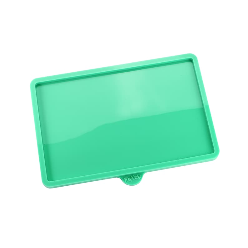 May include: A green silicone tray with a raised edge and the word "Reflat" printed on the bottom.