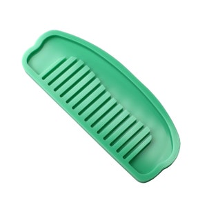 Peut inclure: Un peigne en plastique vert avec une poignée incurvée et une rangée de dents. Le peigne est conçu pour démêler les cheveux.