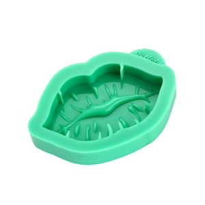 May include: Green silicone mould shaped like a pair of lips. The mould has a detailed lip texture and is designed for making resin crafts.