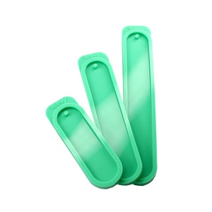 May include: Three green silicone moulds for making resin bookmarks. The moulds are rectangular with rounded edges and have a hole at the top for attaching a ribbon or string. The moulds are labelled "Remarkable" on the top.