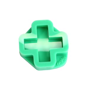 Könnte beinhalten: Eine grüne Silikonform in Form eines Kreuzes. Die Form hat ein Wirbelmuster und das Wort "frolic" ist auf der Unterseite aufgedruckt.