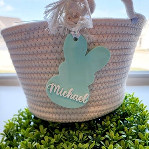 May include: A white rope basket with a light blue bunny-shaped tag that says "Michael".