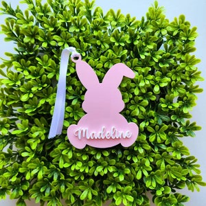 May include: Pink bunny-shaped Easter decoration with the name "Madeline" written in white on the front.
