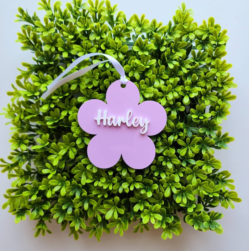 May include: Pink flower-shaped name tag with the name "Harley" written in white letters.