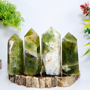 May include: Four green and white crystal points on a wooden stand. The crystals are polished and have a natural, organic look.