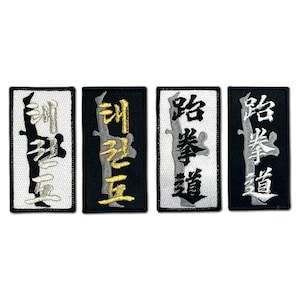May include: Four embroidered patches with black and white lettering on a white background. The patches are rectangular and have black borders. The lettering on the patches reads "跆拳道" in different styles.