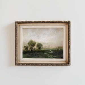 May include: An antique-style framed landscape painting. The artwork depicts a serene, misty scene with a winding river, trees, and a soft, muted color palette of greens, browns, and creams. The ornate gold frame adds a touch of vintage elegance to the artwork.
