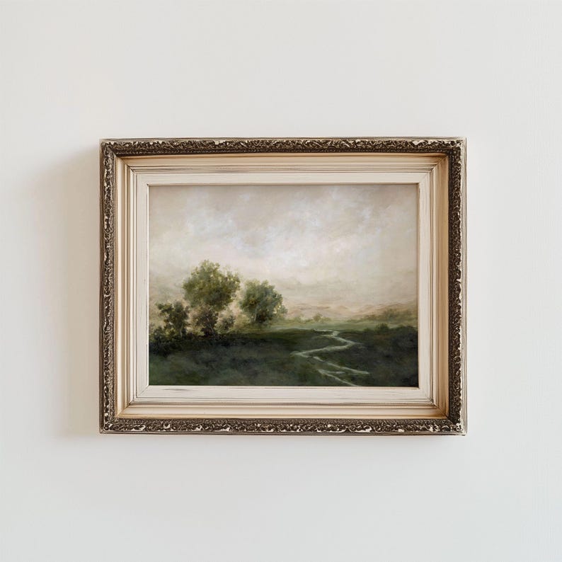 May include: An antique-style framed landscape painting. The artwork depicts a serene, misty scene with a winding river, trees, and a soft, muted color palette of greens, browns, and creams. The ornate gold frame adds a touch of vintage elegance to the artwork.