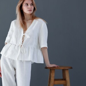 Puede incluir: Un conjunto de pijama de lino blanco con una parte superior con volantes y un lazo en el escote. Los pantalones son de pierna ancha y el conjunto est&aacute; hecho de lino suave y transpirable.