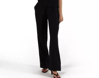 May include: A black sleeveless top with a v-neckline and black wide-leg pants. The model is wearing black sandals.