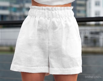 May include: White linen shorts with a high waist and a gathered elastic waistband. The shorts have a relaxed fit and a cuffed hem.