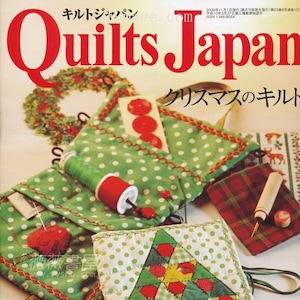 Può includere: Una copertina di rivista per Quilts Japan, che presenta una trapunta patchwork verde e rossa con un motivo a forma di albero di Natale. Il testo della copertina recita "Quilts Japan" e "Trapunte di Natale".
