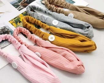 Può includere: Cinque fasce per capelli colorate con un bottone su ciascuna. Le fasce sono realizzate in un tessuto morbido e a coste e sono disponibili in rosa, giallo, grigio, marrone e bianco.