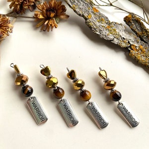 May include: Four gold and brown beaded keychains with silver tags that read "Warrior".