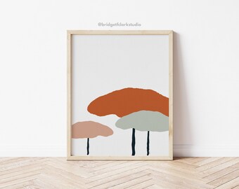 May include: Framed art print featuring an abstract design of three mushroom-like shapes in shades of orange, pink, and green against a white background. The artwork is in a wooden frame and is displayed on a white wall.