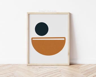 May include: A framed print with a minimalist abstract design featuring a dark blue circle and a half-circle in a burnt orange colour.