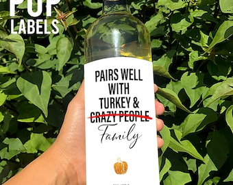 May include: White wine bottle with a printable label that says "Pairs well with turkey & crazy people Family" with a pumpkin graphic. The label is from PopLabels.