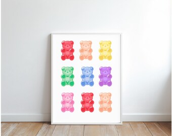 Puede incluir: Una impresión enmarcada con nueve ilustraciones de ositos de goma coloridos. Los ositos están dispuestos en una cuadrícula, mostrando una variedad de colores como rojo, naranja, amarillo, verde, azul, morado y rosa. La obra se exhibe sobre un fondo blanco.