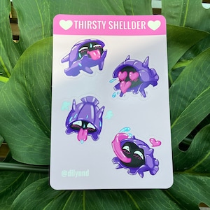 May include: A sticker sheet featuring four different cartoon illustrations of a purple and black Shellder Pokemon with various expressions, including a tongue sticking out, hearts for eyes, and a drool effect. The sticker sheet has a pink background with the text "THIRSTY SHELLDER" and the text "@dilyand" at the bottom.