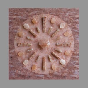 Könnte beinhalten: Eine kreisförmige Anordnung von rosa und weißen Sunstone-Kristallen auf einem rosa Marmoruntergrund. Die Kristalle sind in einem Kreis angeordnet, mit einem größeren rosa Sunstone-Kristall in der Mitte.