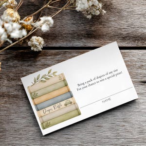 May include: A rectangular white diaper raffle card featuring a stack of illustrated books in muted green, beige, and blue tones. The text reads: Bring a pack of diapers of any size For your chance to win a special prize! Diaper Raffle NAME.