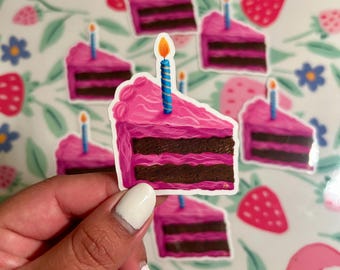 Può includere: Un set di adesivi a forma di fetta di torta rosa e marrone con una candela blu e gialla in cima. Gli adesivi sono su uno sfondo bianco con un motivo floreale.