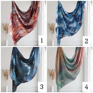 May include: Four different patterned scarves, each displayed on a white wall with a plant in the corner. The scarves are in shades of blue, orange, pink, and green.