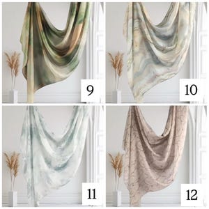 May include: Four different patterned scarves in a variety of colors, including green, brown, white, and pink. The scarves are draped over a white surface with a white trim.