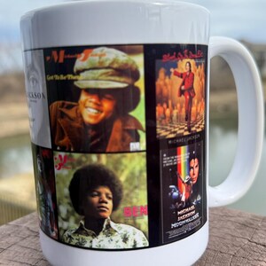 May include: White ceramic mug featuring a collage of Michael Jackson album covers. The mug displays images from his solo career, including album art from "Got to Be There" and "Ben". The mug has a white handle.