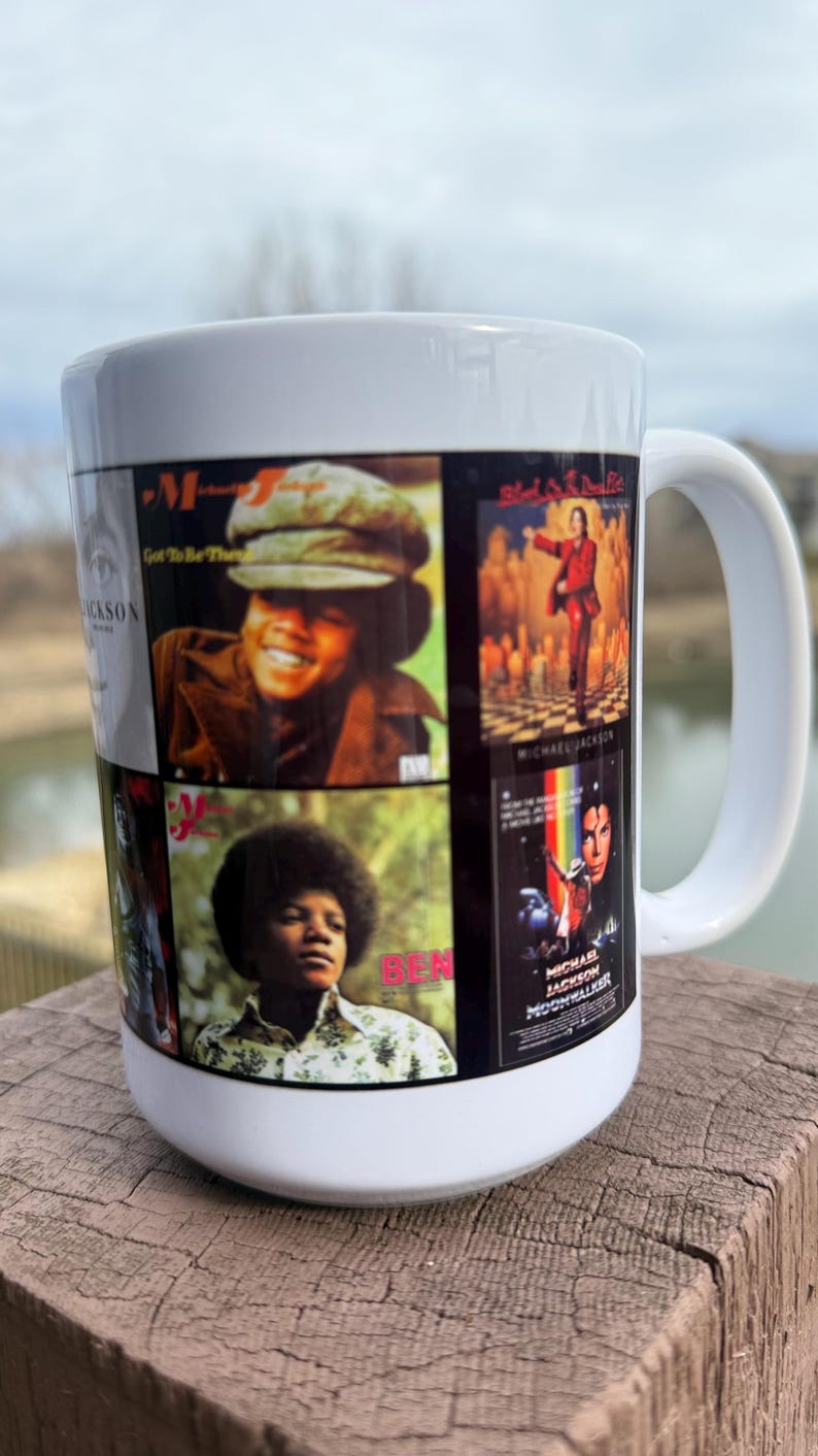 May include: White ceramic mug featuring a collage of Michael Jackson album covers. The mug displays images from his solo career, including album art from "Got to Be There" and "Ben". The mug has a white handle.