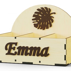 K&ouml;nnte beinhalten: Ein Holzorganizer mit drei F&auml;chern, einem braunen Blattdesign und dem Namen "Emma" auf der Vorderseite.