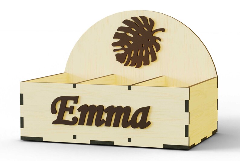 K&ouml;nnte beinhalten: Ein Holzorganizer mit drei F&auml;chern, einem braunen Blattdesign und dem Namen "Emma" auf der Vorderseite.