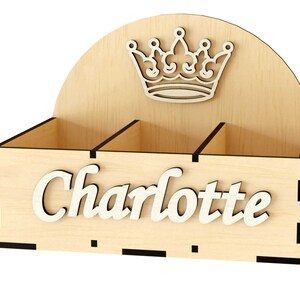 K&ouml;nnte beinhalten: Holzorganizer mit drei F&auml;chern und einem Kronendesign auf der Oberseite. Der Organizer tr&auml;gt den Namen "Charlotte" auf der Vorderseite.