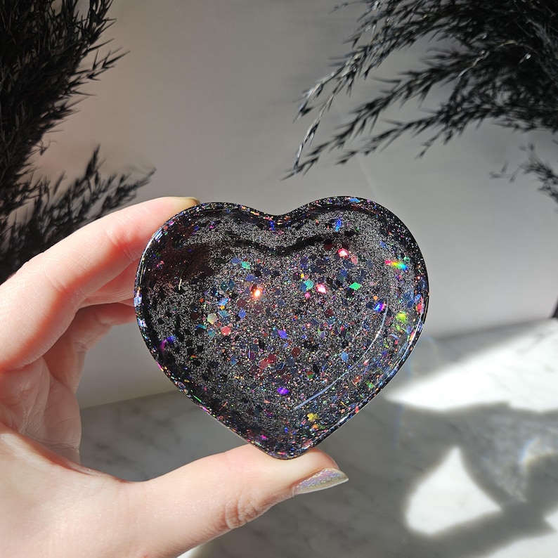 May include: A black heart-shaped resin dish with iridescent glitter embedded in the resin.