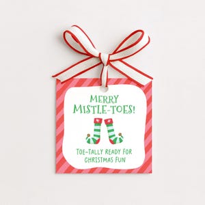 May include: A Christmas gift tag with a red and white striped ribbon. The tag has a red and pink striped border and features the text "MERRY MISTLE-TOES!" and "TOE-TALLY READY FOR CHRISTMAS FUN" with elf feet illustrations.