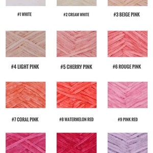 May include: Twelve yarn samples in various shades of pink, red, white, and purple. The yarn is arranged in a grid pattern with each sample labeled with a number and color name.