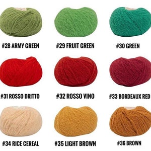 Puede incluir: Nueve ovillos de lana en diferentes colores, incluyendo verde militar, verde fruta, verde, rojo, burdeos, beige y marr&oacute;n. Cada ovillo est&aacute; etiquetado con un n&uacute;mero y un nombre de color.
