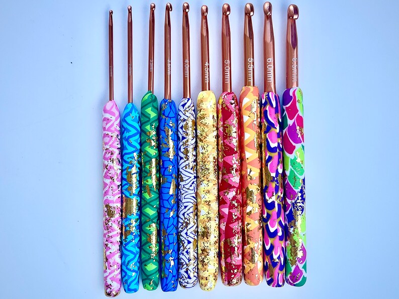 Puede incluir: Un juego de ocho agujas de crochet de colores con detalles dorados. Las agujas est&aacute;n hechas de metal y tienen una variedad de patrones en los mangos. Las agujas est&aacute;n etiquetadas con sus tama&ntilde;os en mil&iacute;metros: 3,5 mm, 4,0 mm, 4,5 mm, 5,0 mm, 5,5 mm, 6,0 mm, 6,5 mm y 7,0 mm.