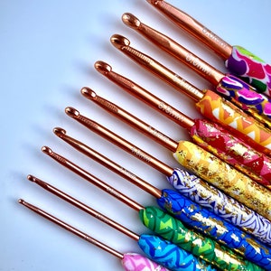 Puede incluir: Un juego de diez agujas de crochet con mangos coloridos y estampados. Las agujas est&aacute;n hechas de metal dorado rosa y tienen tama&ntilde;os que van desde 2,5 mm hasta 6,0 mm.