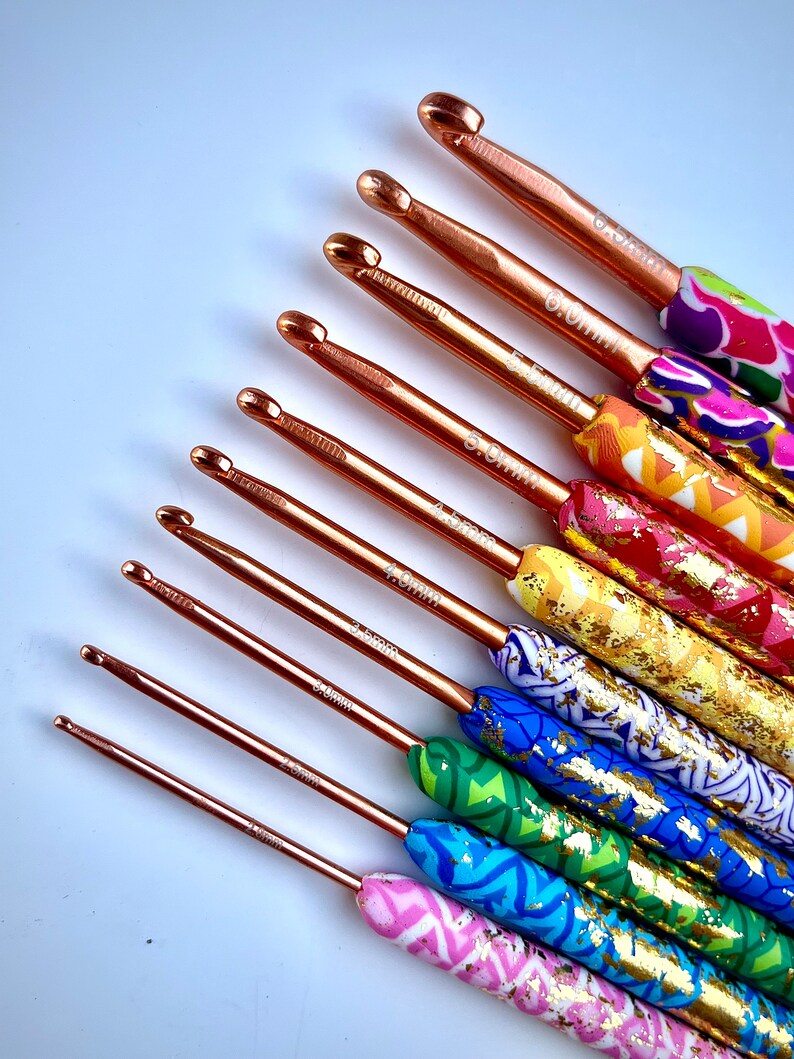 Puede incluir: Un juego de diez agujas de crochet con mangos coloridos y estampados. Las agujas est&aacute;n hechas de metal dorado rosa y tienen tama&ntilde;os que van desde 2,5 mm hasta 6,0 mm.