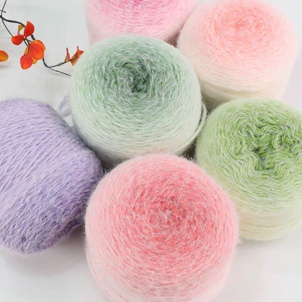 May include: A collection of colorful yarn balls in shades of pink, green, and purple. The yarn appears soft and fluffy, ideal for knitting or crocheting projects. The balls are arranged closely together, showcasing the variety of colors.