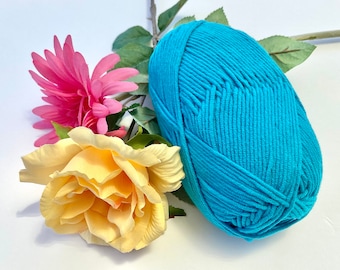 May include: A ball of teal blue yarn with a pink and yellow flower arrangement.