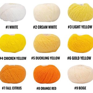 Puede incluir: Nueve ovillos de lana en varios tonos de amarillo, naranja, blanco y beige. La lana est&aacute; dispuesta en tres filas de tres ovillos cada una. Los ovillos est&aacute;n etiquetados con n&uacute;meros y nombres de colores.