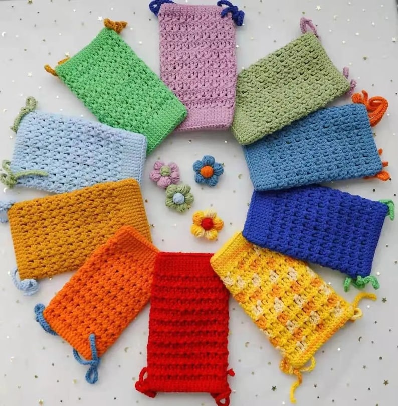 Pu&ograve; includere: Un set di dieci sacchetti con coulisse all'uncinetto in vari colori, tra cui blu, verde, giallo, arancione e rosso. I sacchetti sono disposti in cerchio su una superficie bianca.